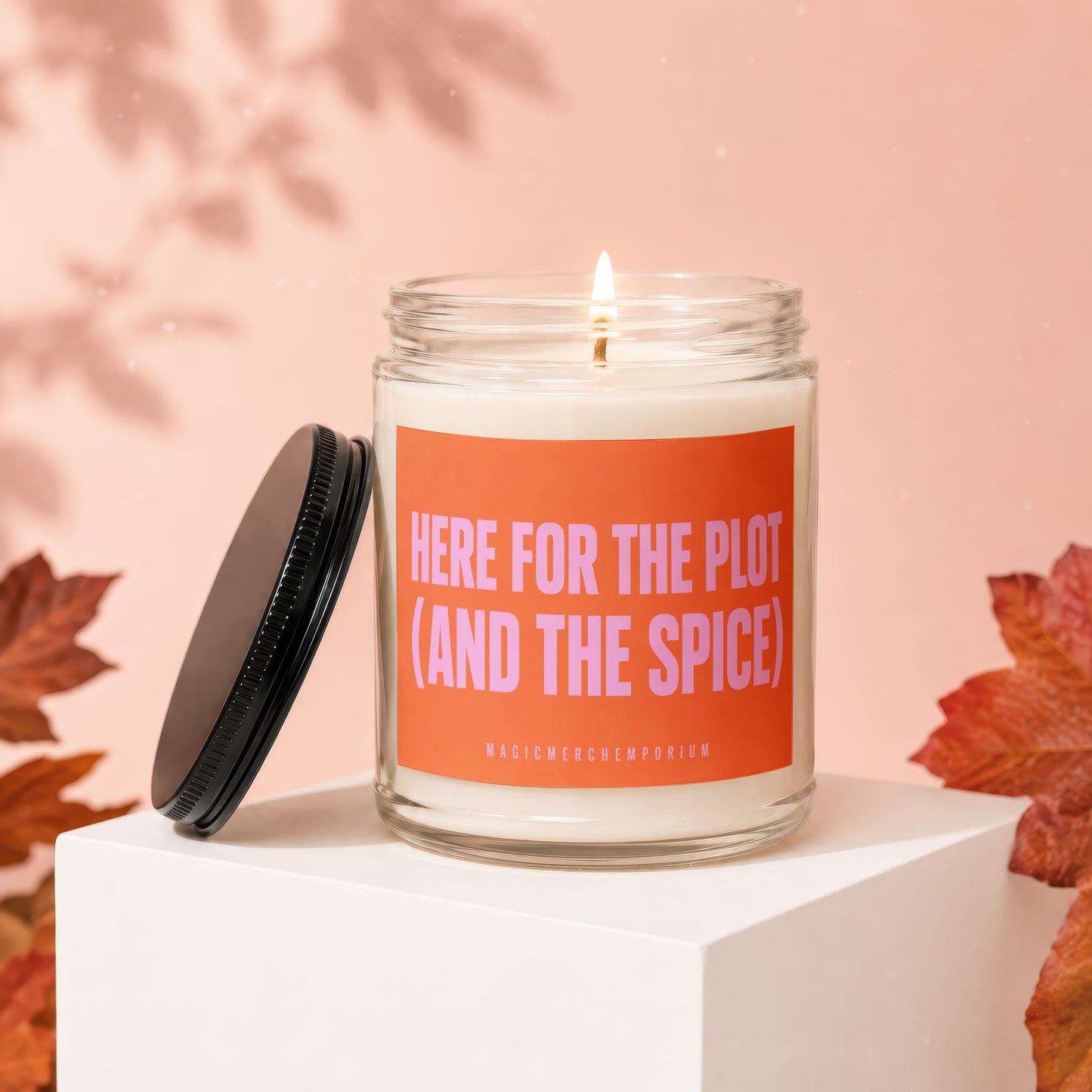 Candle with orange label reading "HERE FOR THE PLOT (AND THE SPICE)".
