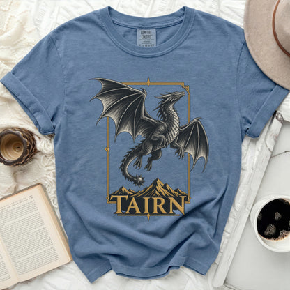 Blue t-shirt with black dragon design over mountains and "TAIRN" text.