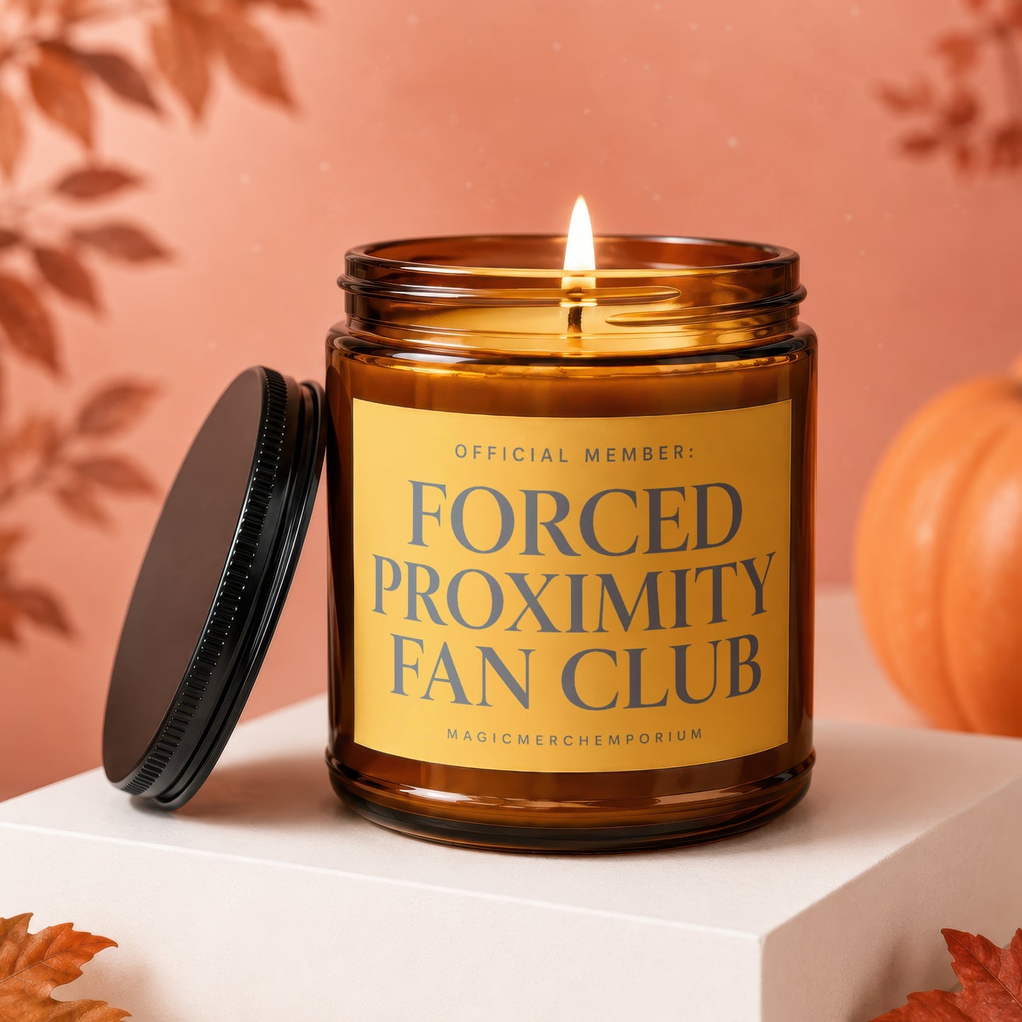 Amber candle with lit wick and "Forced Proximity Fan Club" text on label.