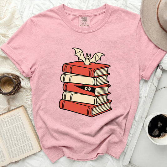 Pink t-shirt with a cartoon stack of books and a bat graphic.