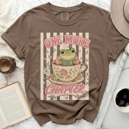 Brown t-shirt with a frog reading in a teacup and "ONE MORE CHAPTER" text.