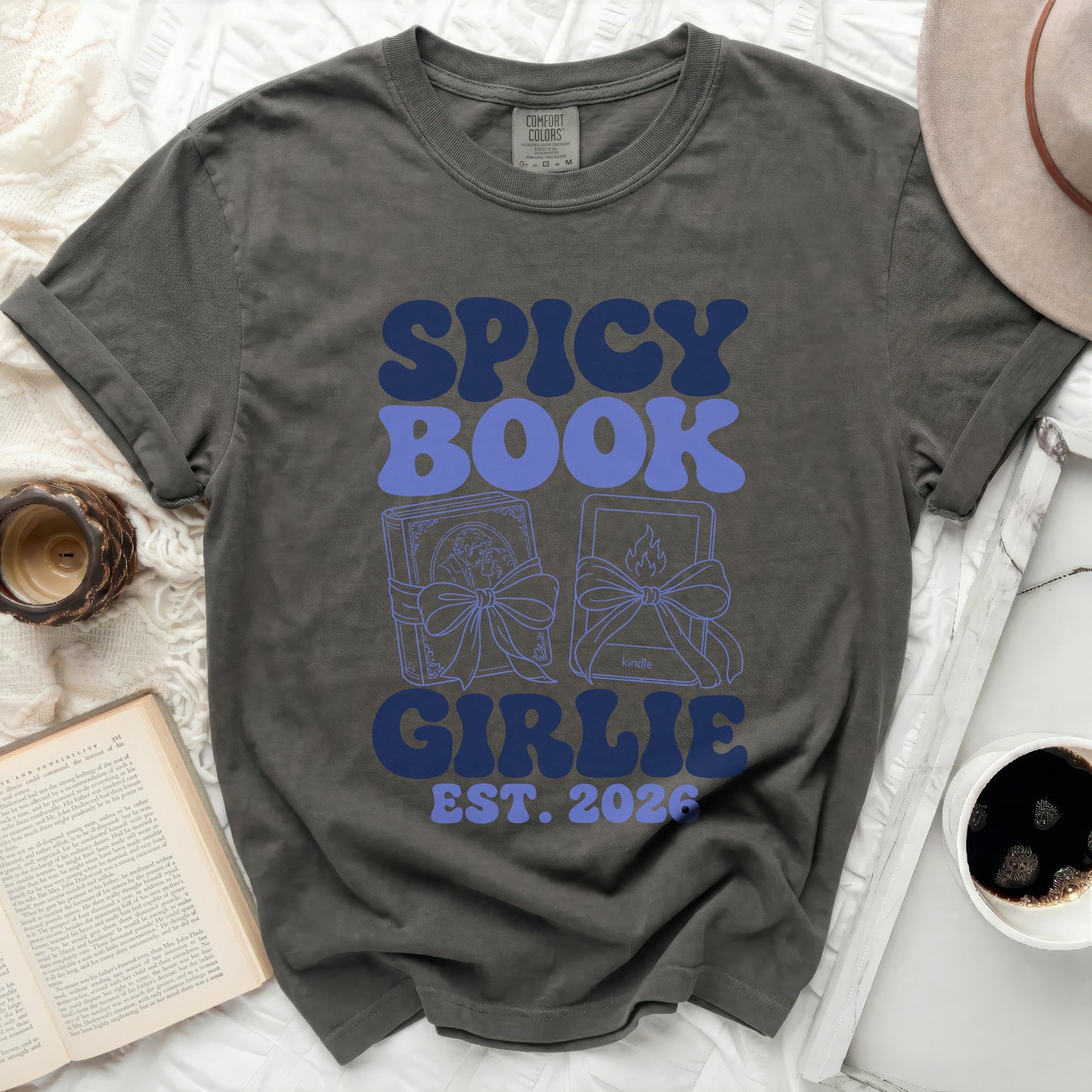 Dark gray t-shirt with "SPICY BOOK GIRLIE EST. 2026" in blue retro font.