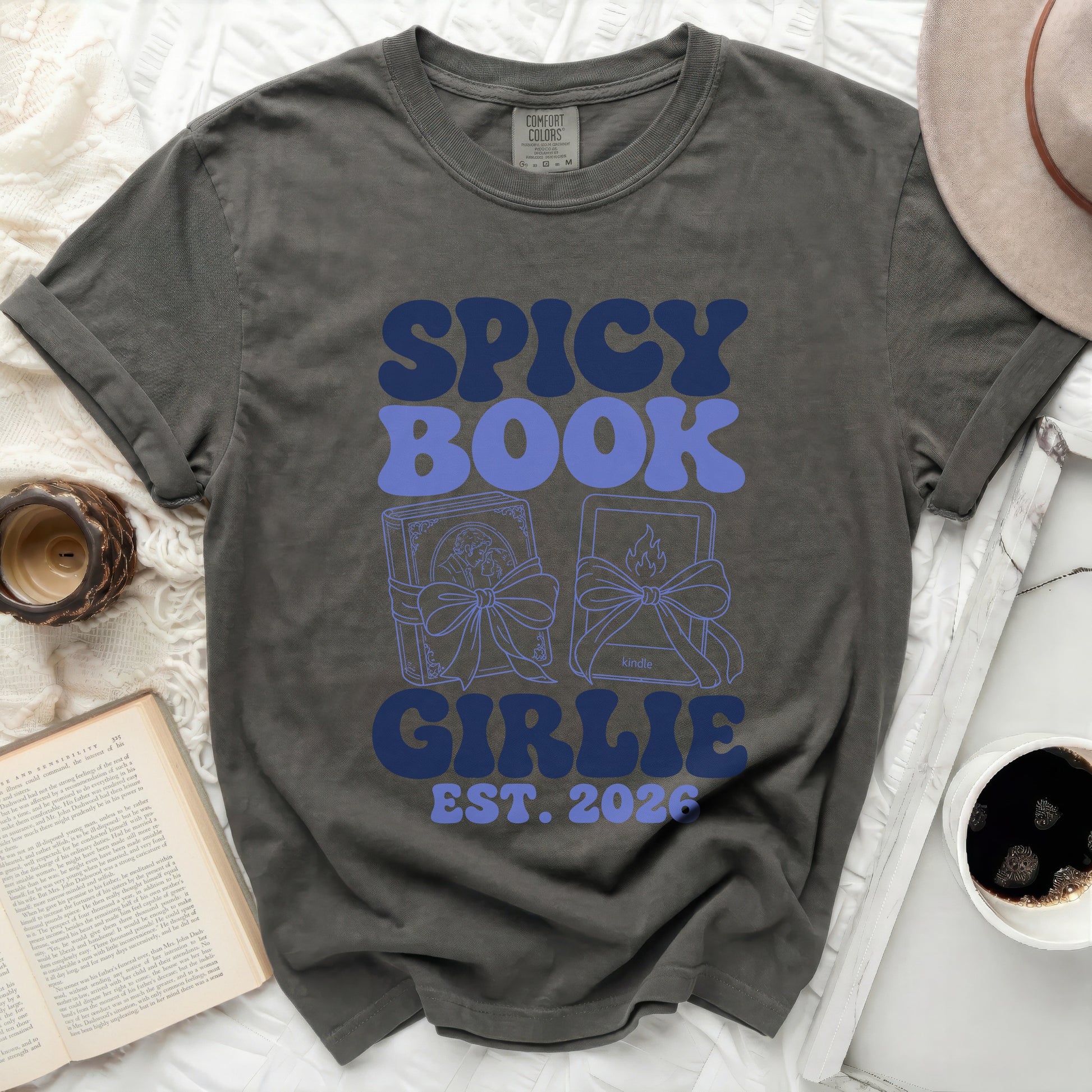 Dark gray t-shirt with "SPICY BOOK GIRLIE EST. 2026" in blue retro font.