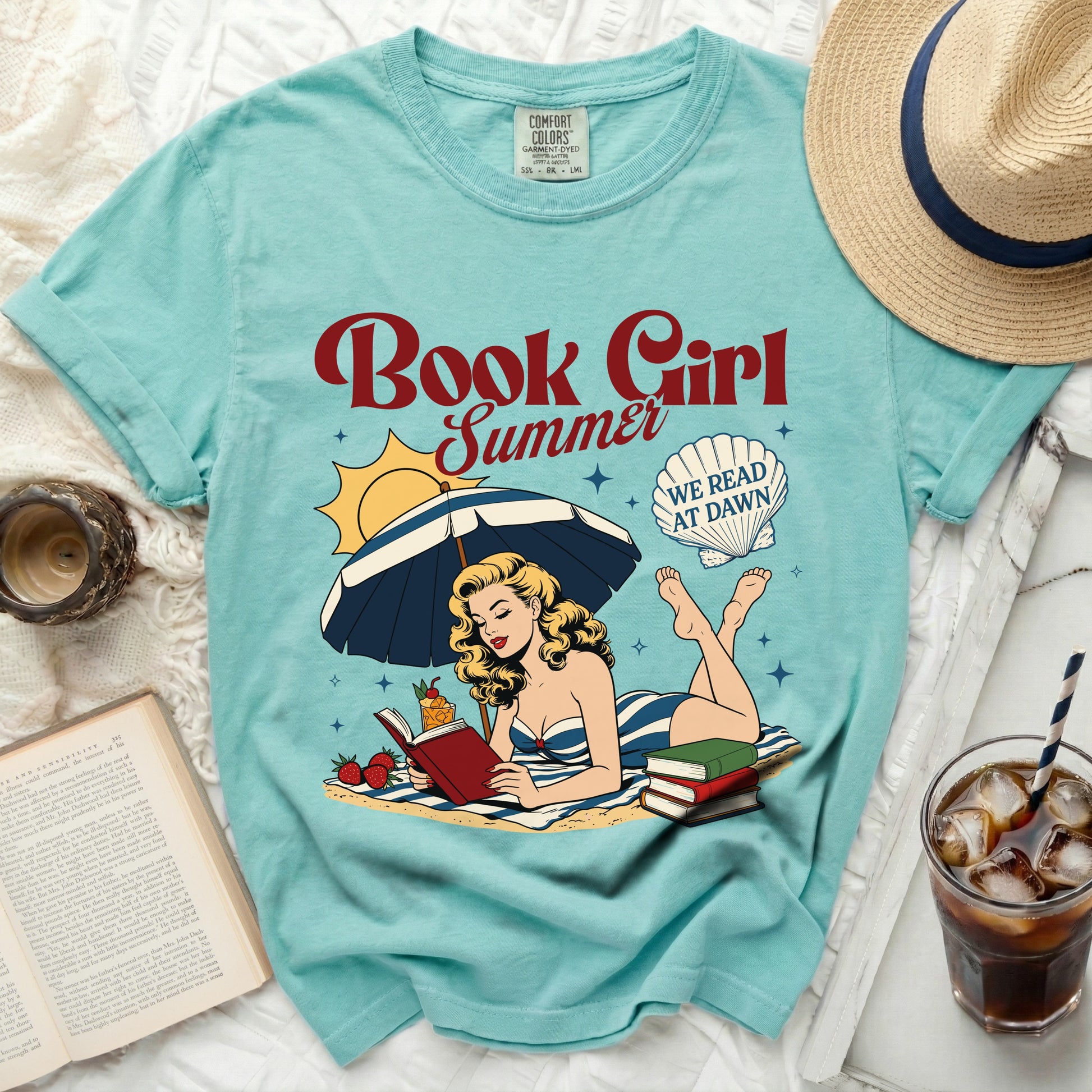 Comfort Colors 'Book Girl Summer' graphic tee with woman reading on beach.