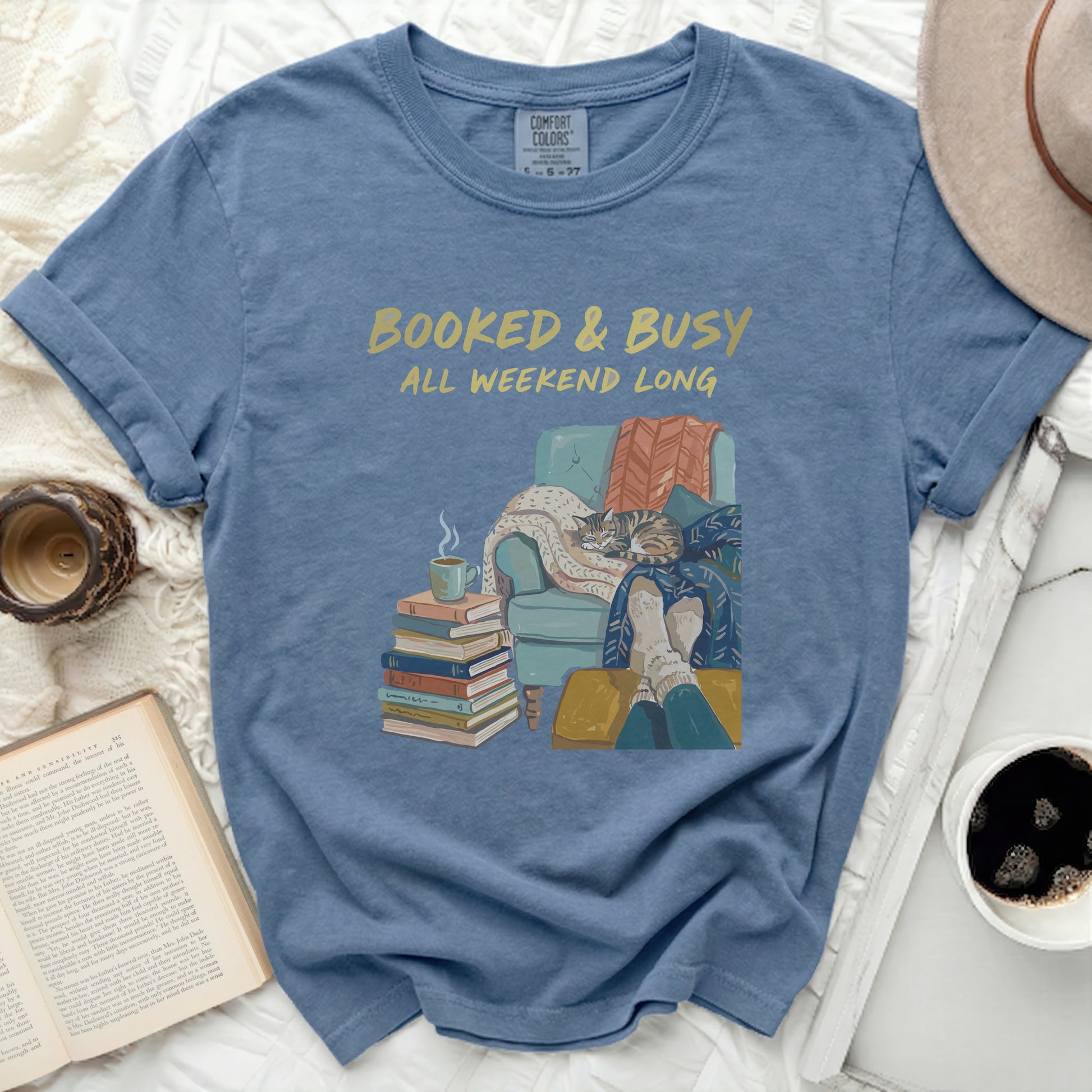 Blue t-shirt with "BOOKED & BUSY ALL WEEKEND LONG" and a cozy cat scene.