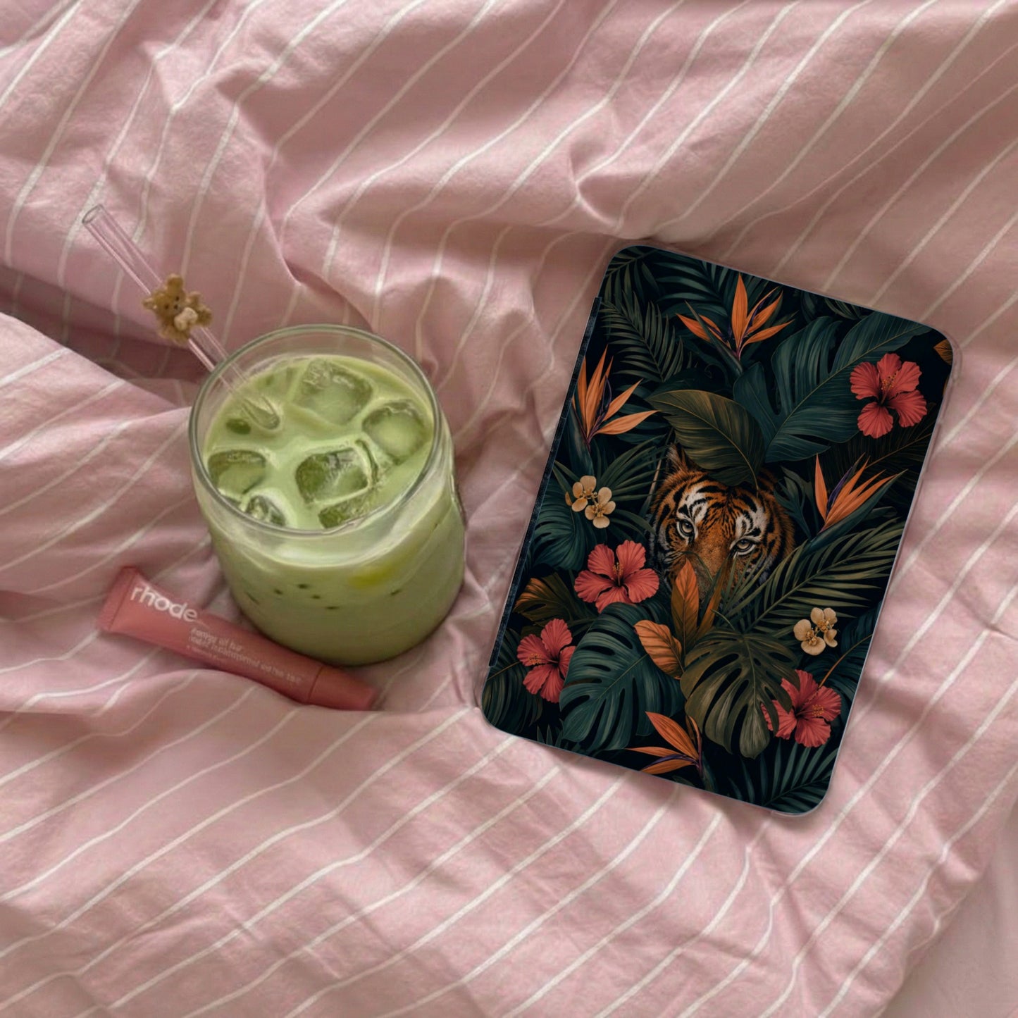 Phone case with tiger and tropical leaves on pink striped fabric.