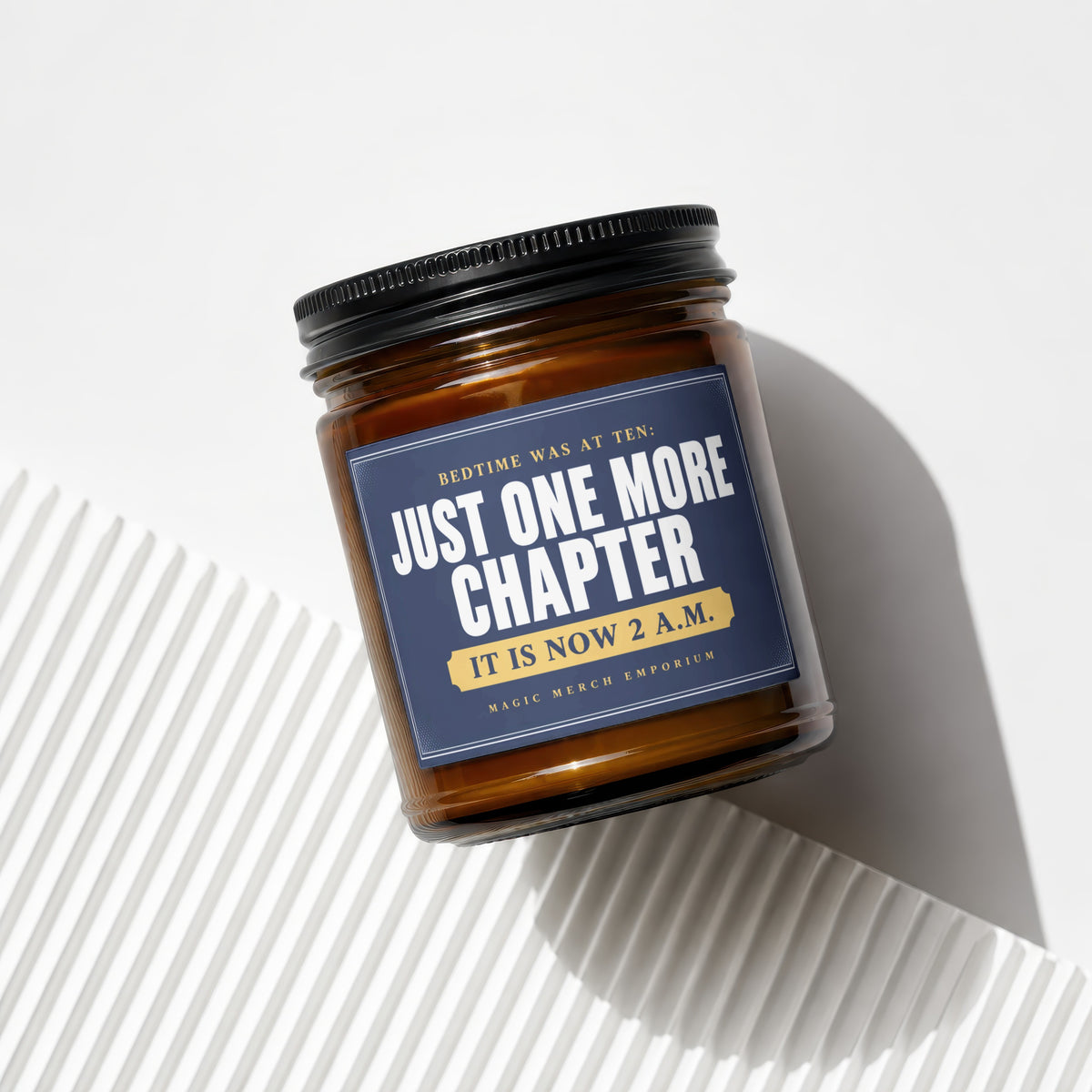 Brown glass candle with navy label reading "Just One More Chapter. It Is Now 2 A.M."