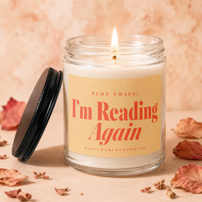 Glass candle with black lid displays "PLOT TWIST: I'm Reading Again" text.