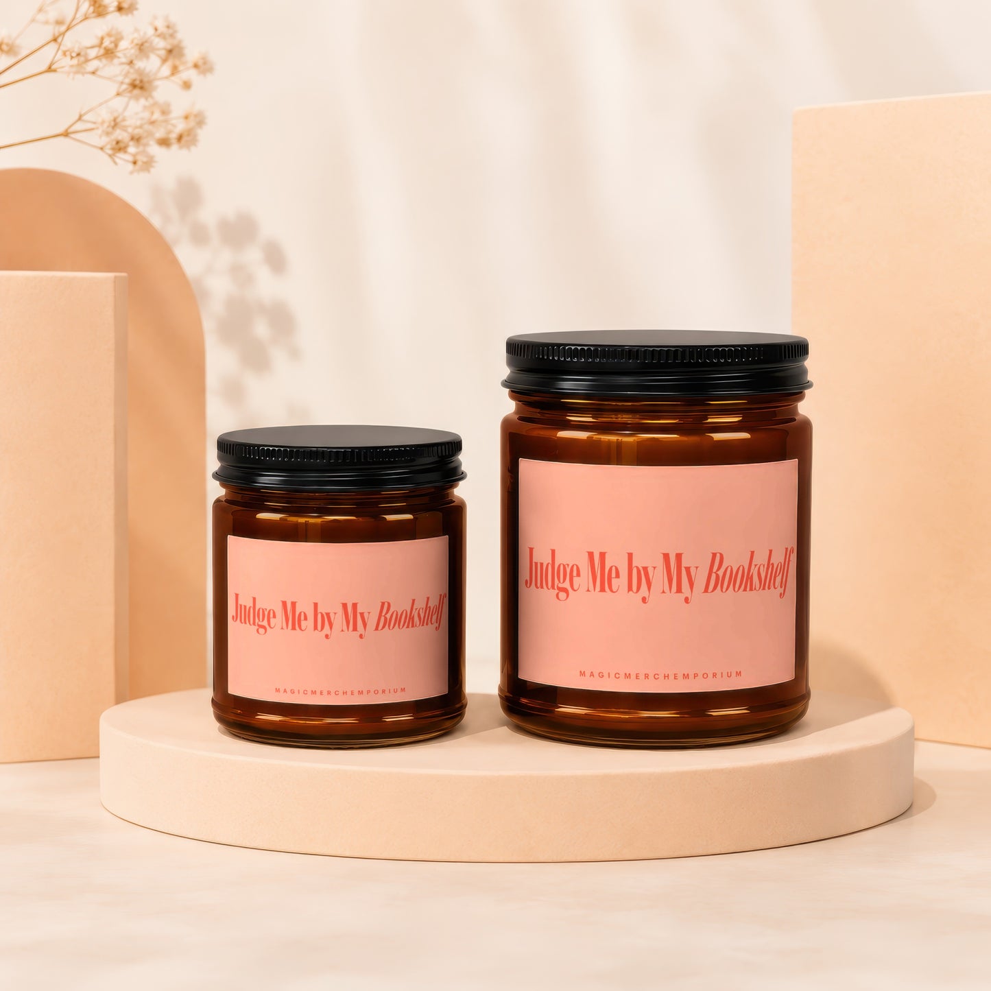 Two brown glass candles with pink labels reading "Judge Me by My Bookshelf."