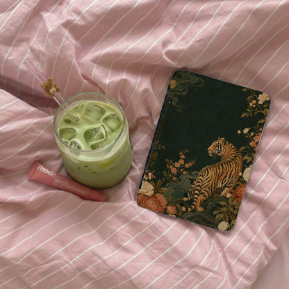 Journal with tiger and floral print next to matcha drink on pink striped bedding.