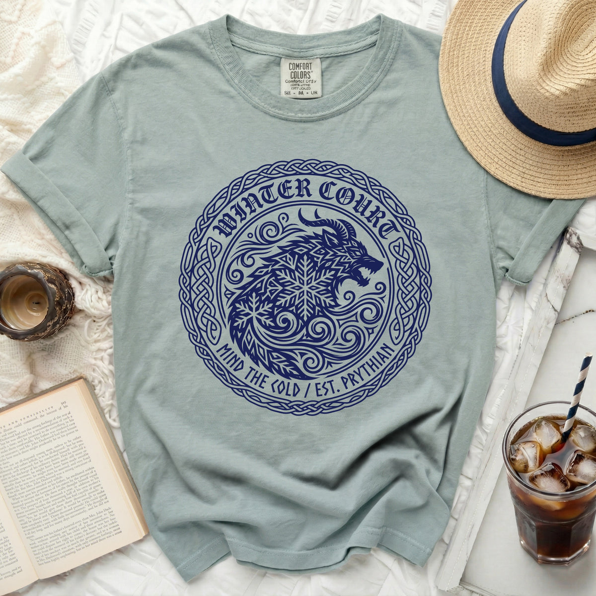 Light blue t-shirt with dark blue circular graphic featuring a wolf, snowflake, and text.