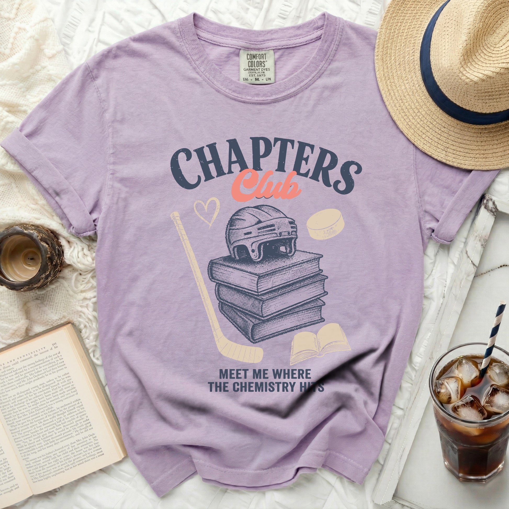 Purple t-shirt with "CHAPTERS Club" text, books, hockey gear, and chemistry graphic.
