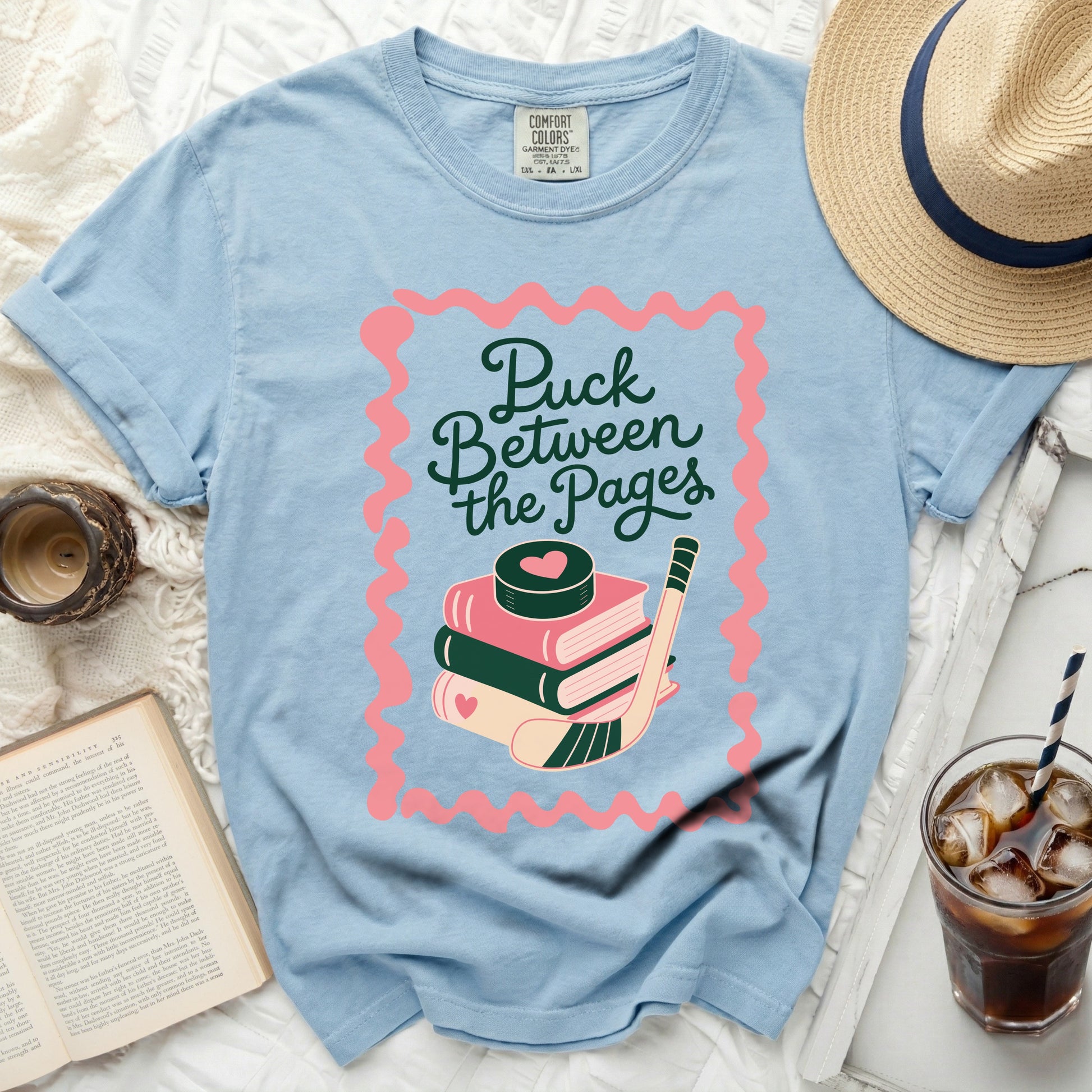 Light blue t-shirt with "Puck Between the Pages" text and hockey graphic.