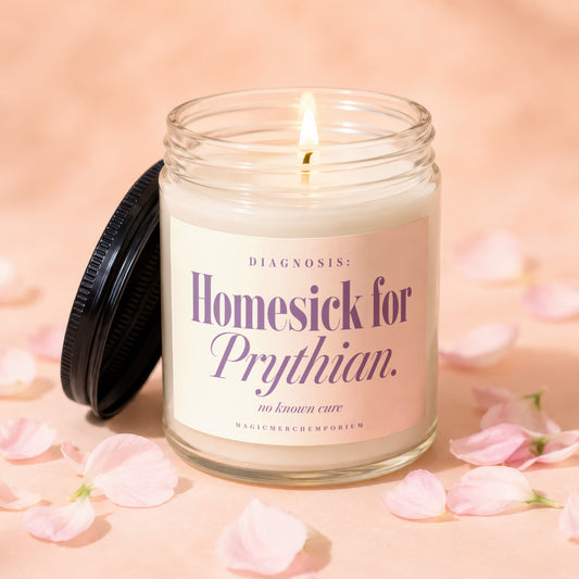 A lit scented candle in a glass jar with a black lid, surrounded by pink petals.