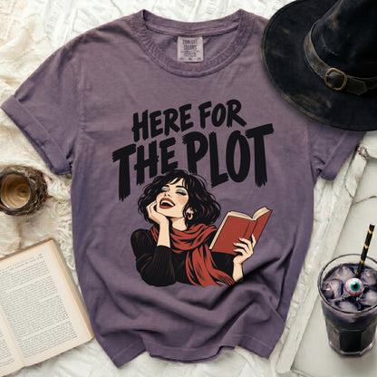 Purple t-shirt with "Here for the Plot" text and illustration of a laughing woman reading.