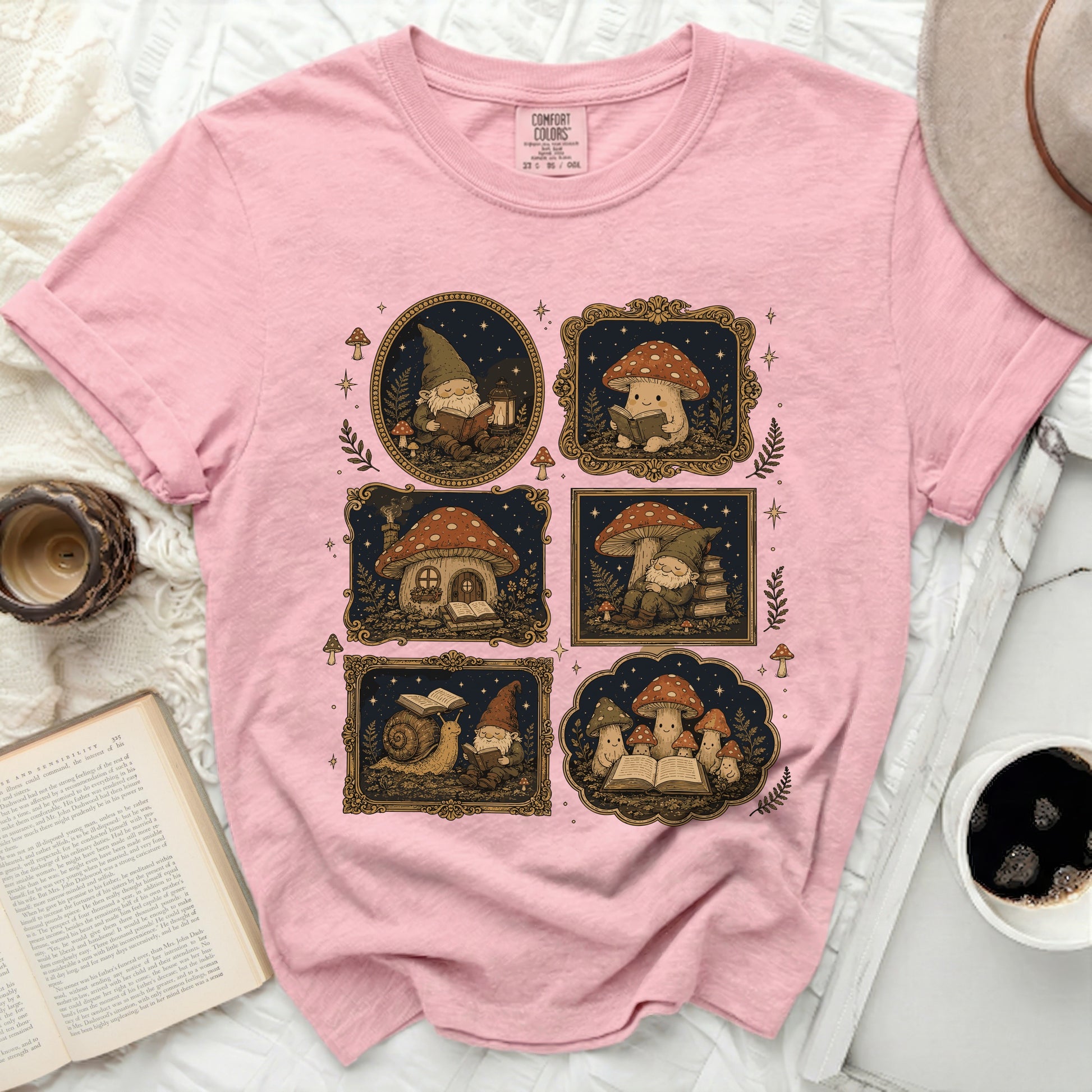 Pink t-shirt with a collage of illustrated gnome and mushroom scenes.