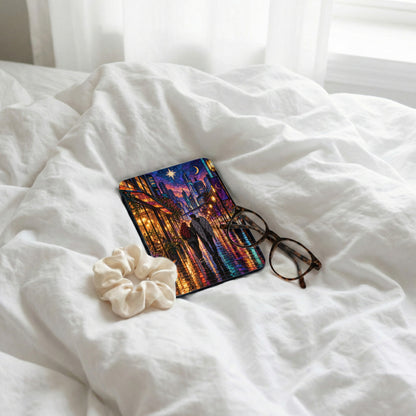 Tablet case with couple walking in city at night, scrunchie, and glasses on white bedding.