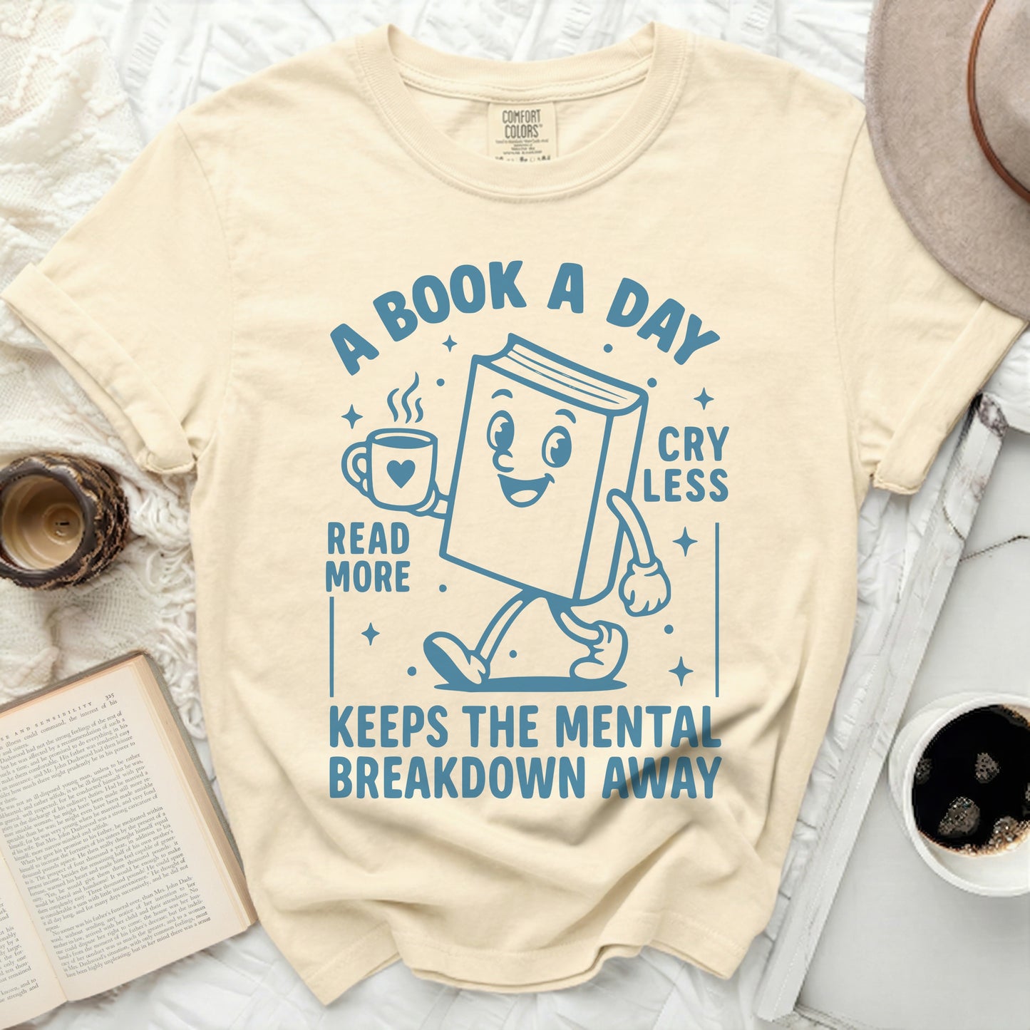 Cream t-shirt with cartoon book reading "A book a day" and "Read more".