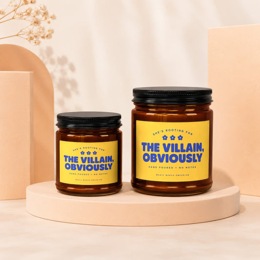 Two amber glass candles with yellow labels that say "The Villain, Obviously".