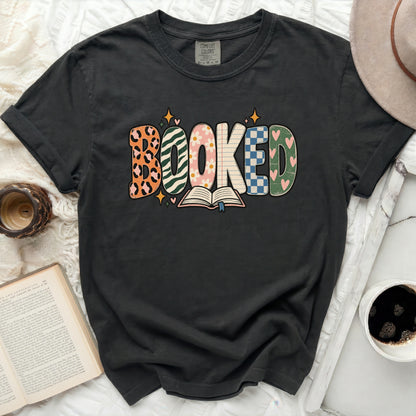 Dark gray t-shirt with "BOOKED" graphic featuring multiple patterns and an open book.