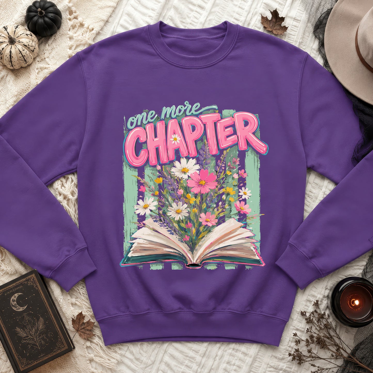 Purple sweatshirt with an open book and flowers reading "one more CHAPTER".