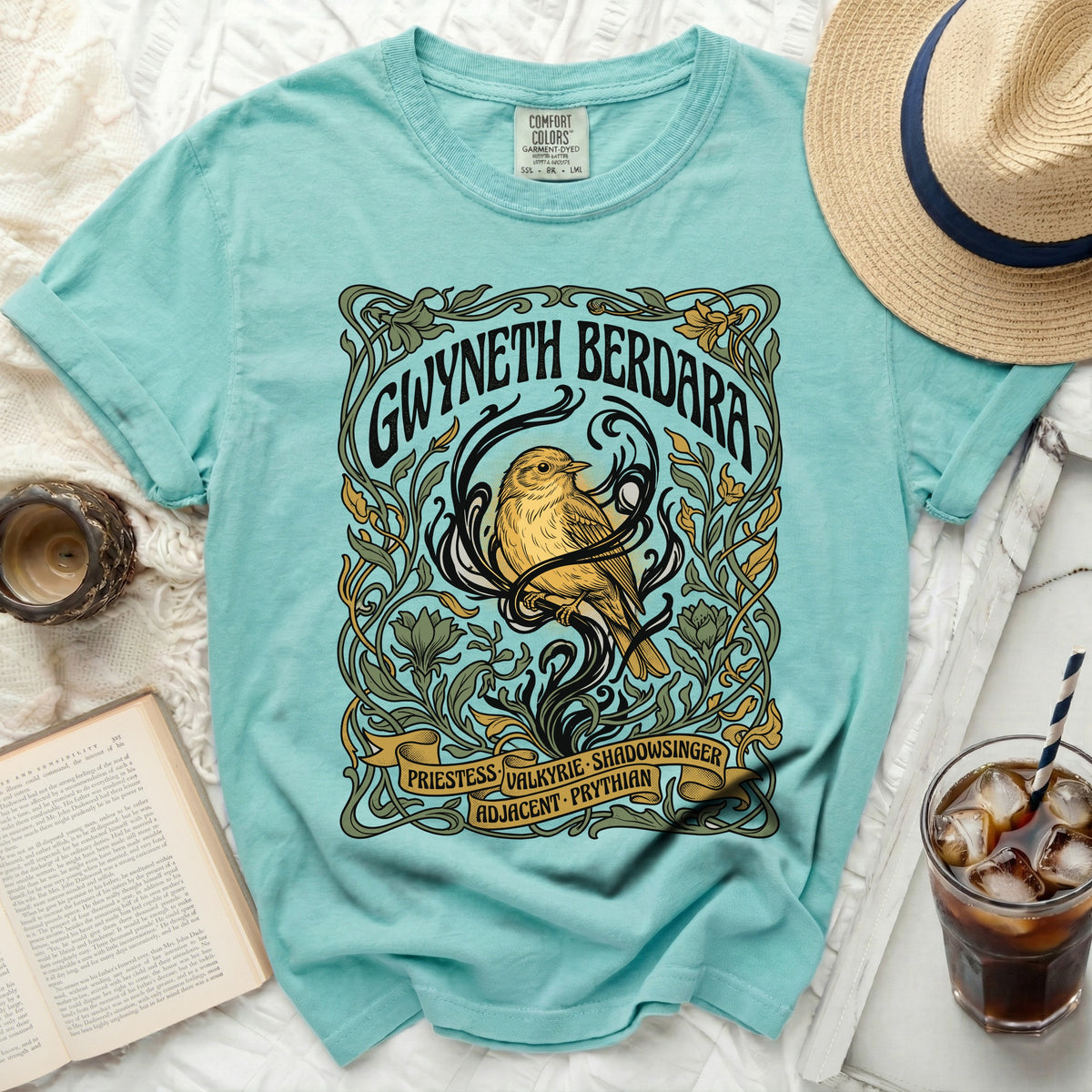 Turquoise t-shirt with a bird and floral art nouveau design, text: GWYNETH BERDARA.