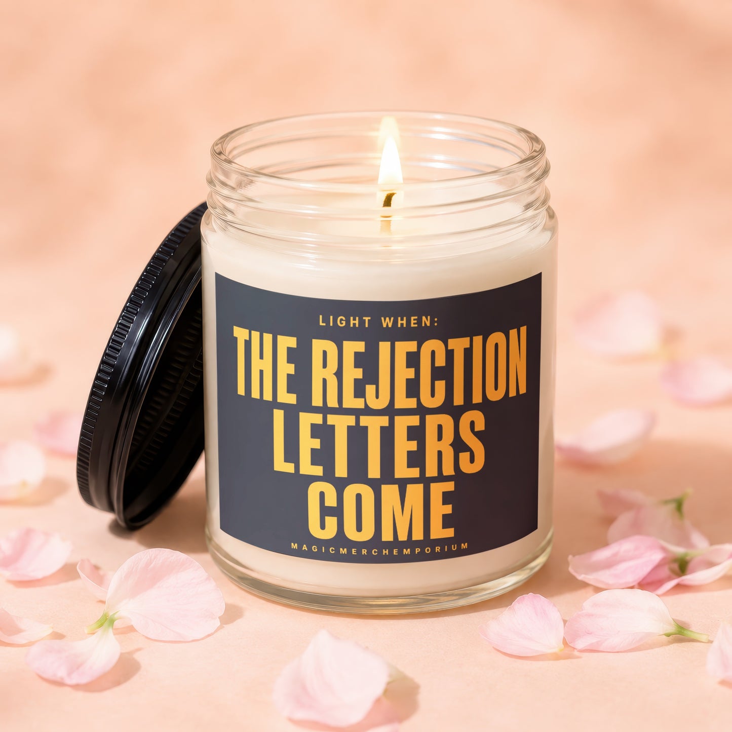 Candle with text "LIGHT WHEN: THE REJECTION LETTERS COME" surrounded by pink petals.