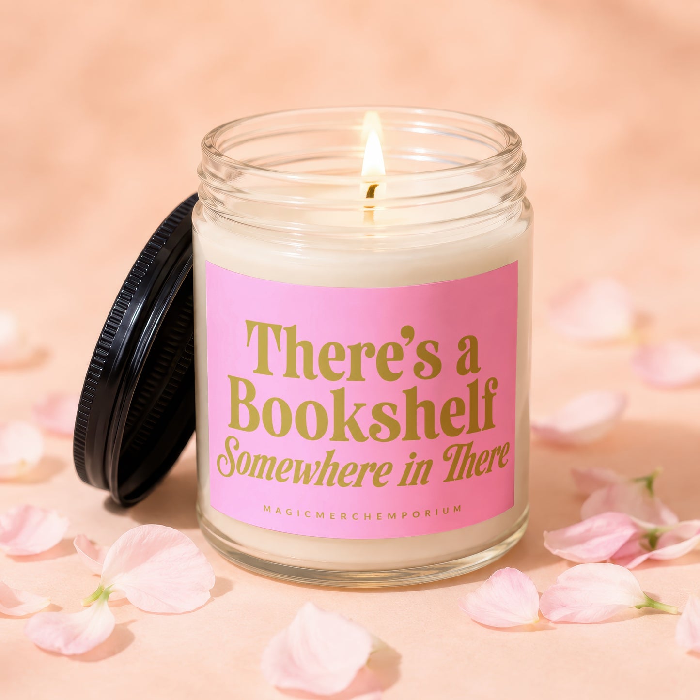 Candle with lit wick on pink label reading "There's a Bookshelf Somewhere in There".