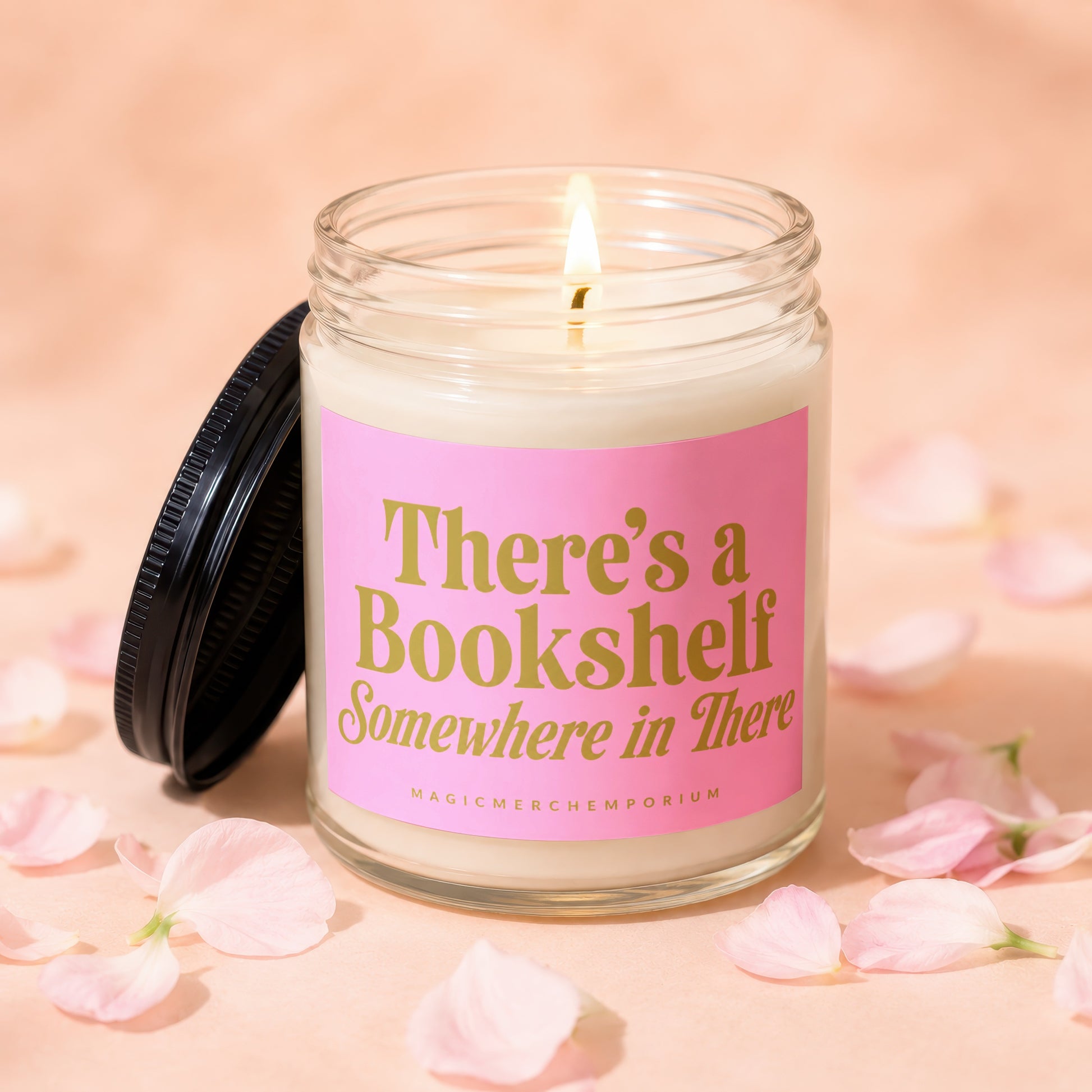Candle with lit wick on pink label reading "There's a Bookshelf Somewhere in There".