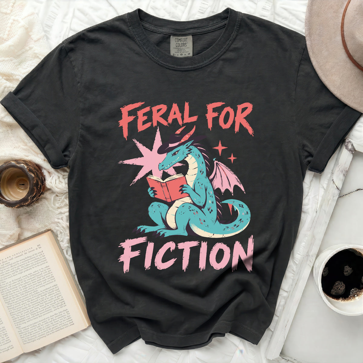 Black t-shirt with dragon reading a book and text "FERAL FOR FICTION".