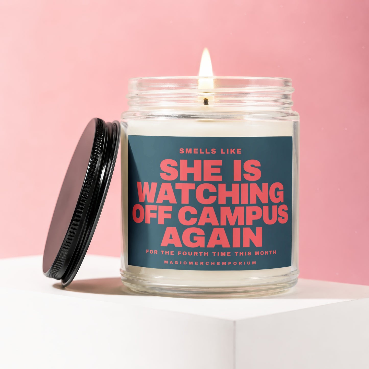 Candle with "She is watching off campus again" text on lidless pink background.