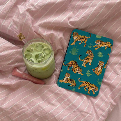 Teal case with tiger pattern next to iced matcha drink on pink striped bedding.