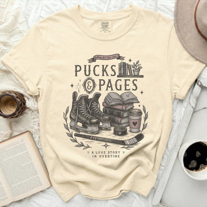 Cream t-shirt with "Pucks & Pages" graphic, ice skates, books, coffee cup, and hockey stick.
