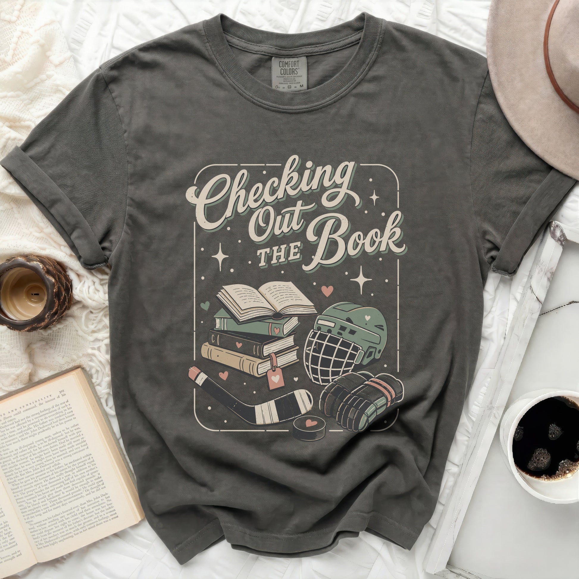 Graphic tee with "Checking The Book" text, hockey gear, and books.