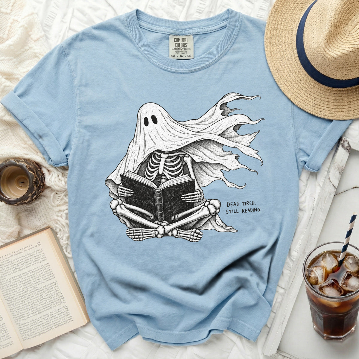 Skeleton ghost reading a book with text "DEAD TIRED. STILL READING."