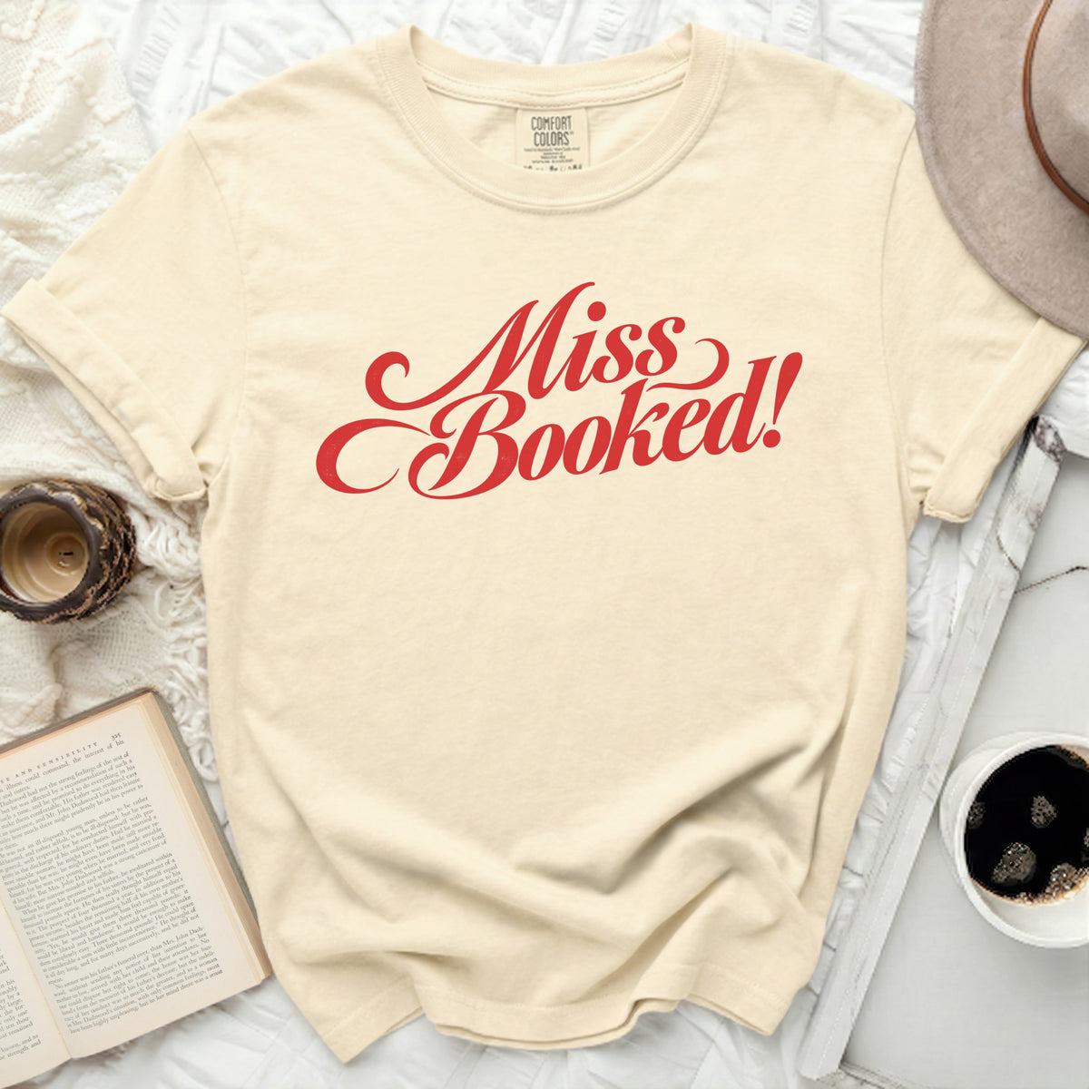 Cream t-shirt with red script text "Miss Booked!" and "Comfort Colors" tag.