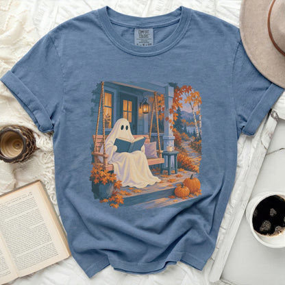 Ghost reading book on porch swing with pumpkins and fall foliage.