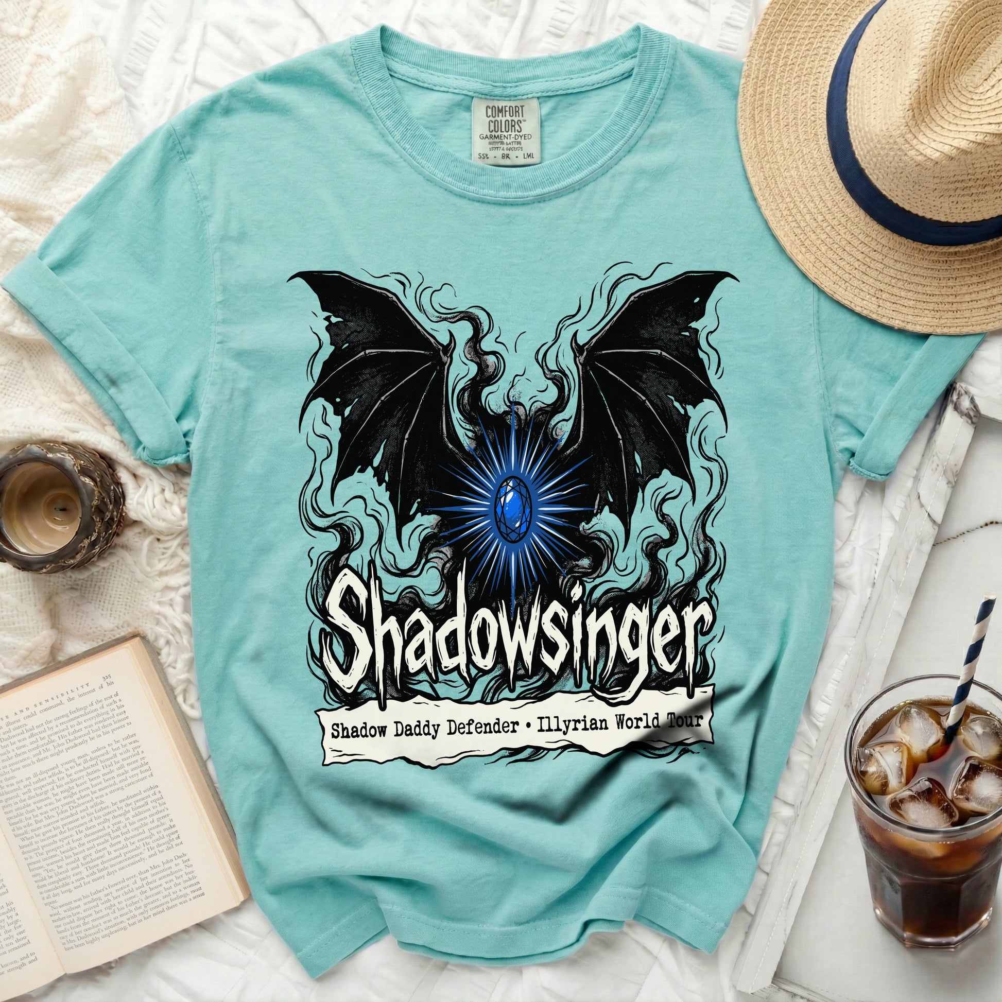 Teal t-shirt with black wings, blue gem, and "Shadowslinger" text.