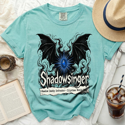 Teal t-shirt with black wings, blue gem, and "Shadowslinger" text.