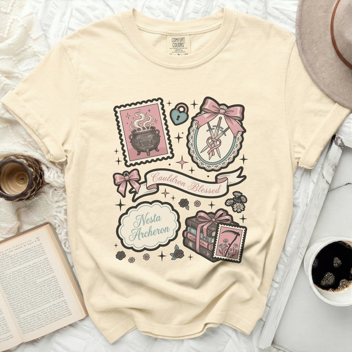 Cream t-shirt with vintage graphic art featuring a cauldron, swords, books, and text.