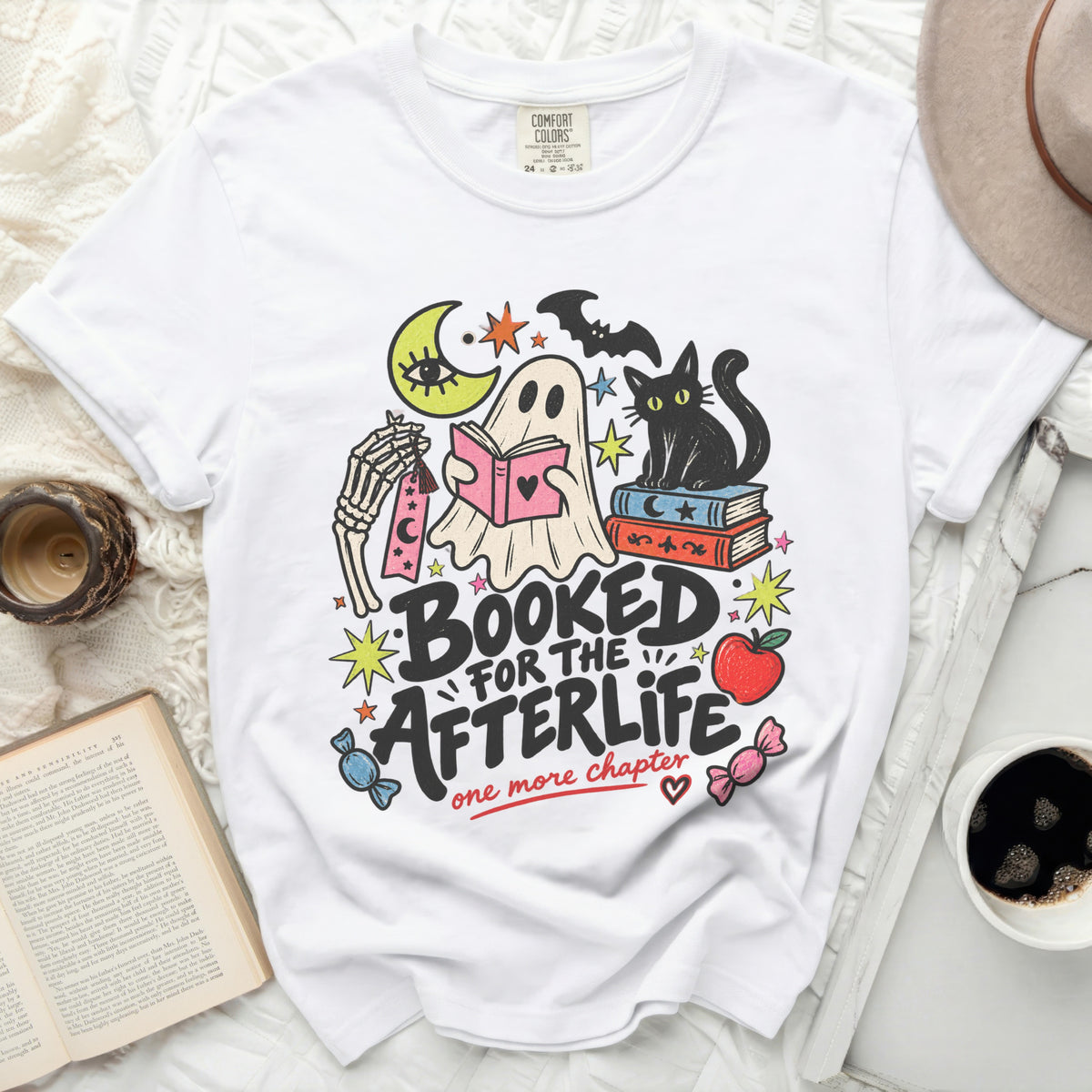 Ghost reading book with cat, moon, and bats, text "Booked for the afterlife"