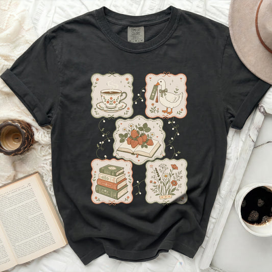 Black t-shirt with four square patches: tea, strawberries, books, and flowers.