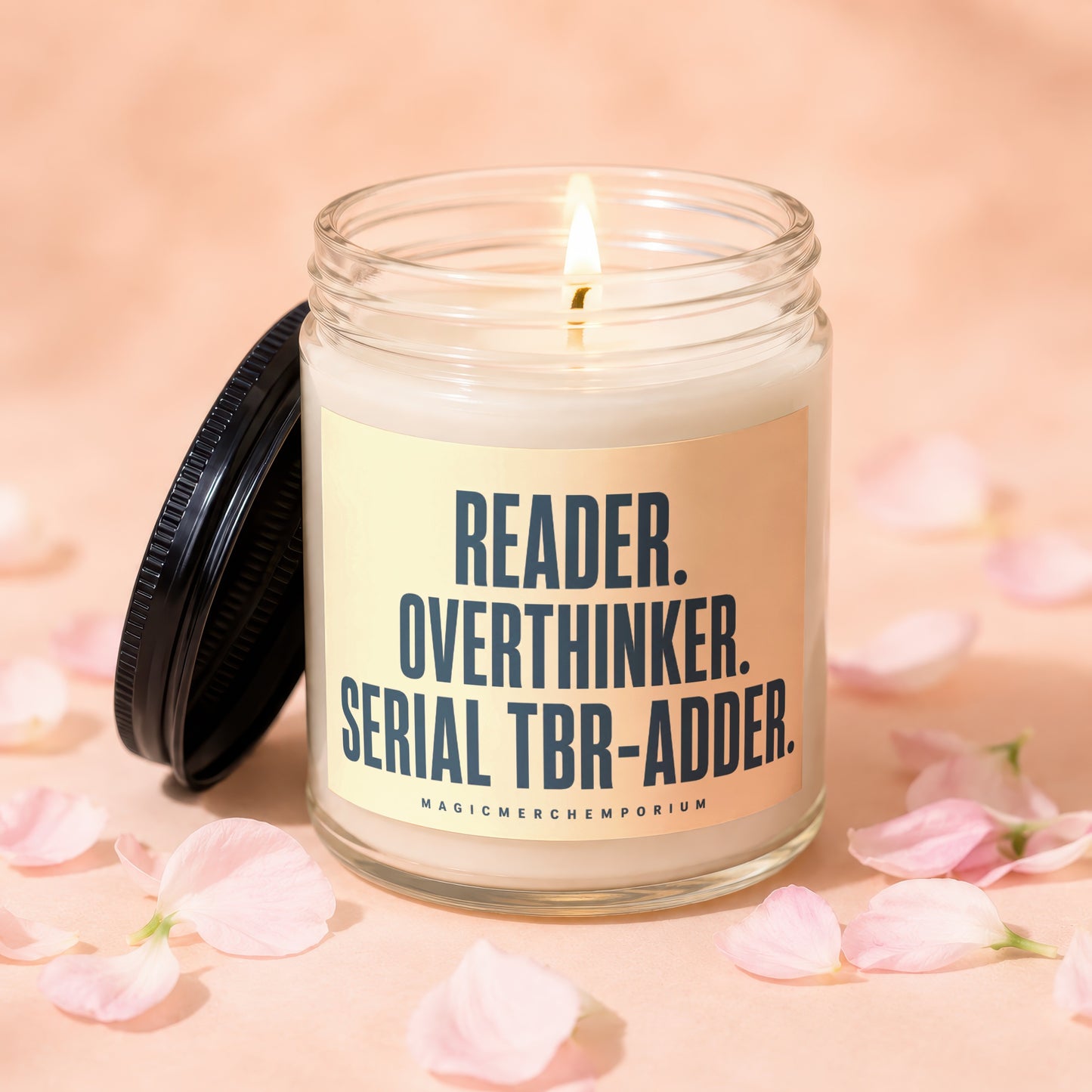 Glass jar candle with lit wick, featuring text "READER. OVERTHINKER. SERIAL TBR-ADDER."