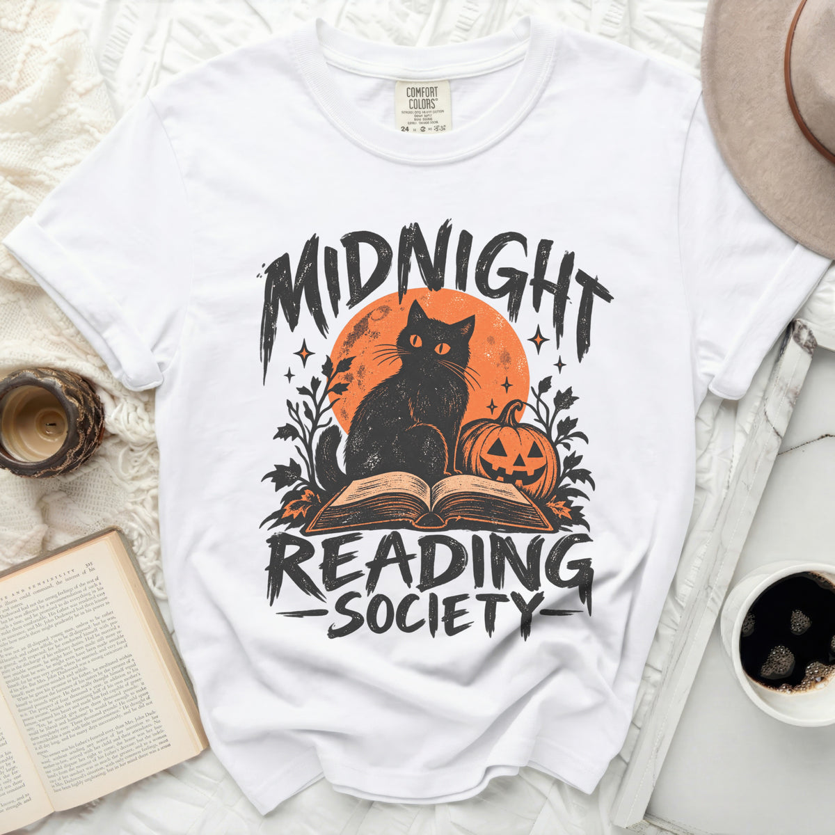 White t-shirt with black cat, pumpkin, and "Midnight Reading Society" text.