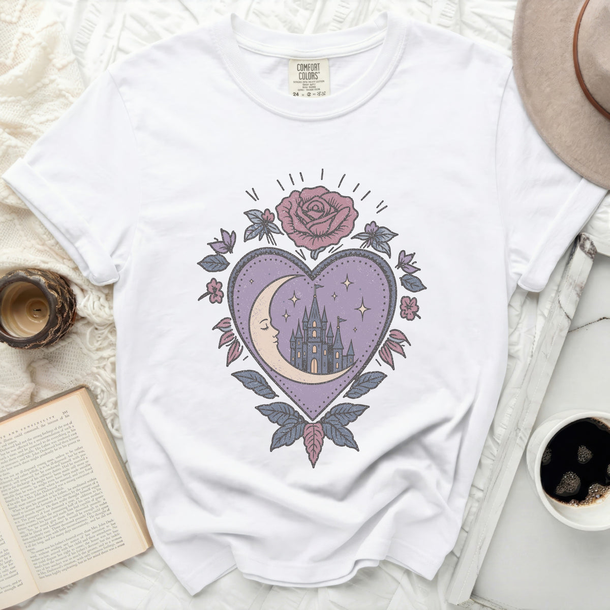 White t-shirt with a pastel graphic of a heart with a crescent moon, castle, and rose.