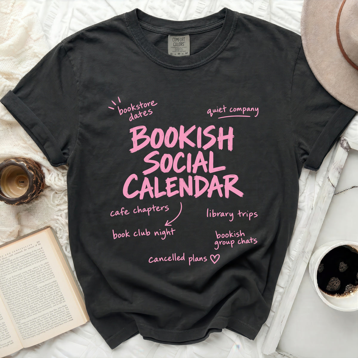 Dark gray Comfort Colors t-shirt with pink text "Bookish Social Calendar" and related activities.