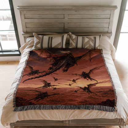 a bed with a large, colorful dragon-themed blanket on it. The blanket has a striking red and orange color scheme and depicts a group of dragons flying across a sunset-like sky.