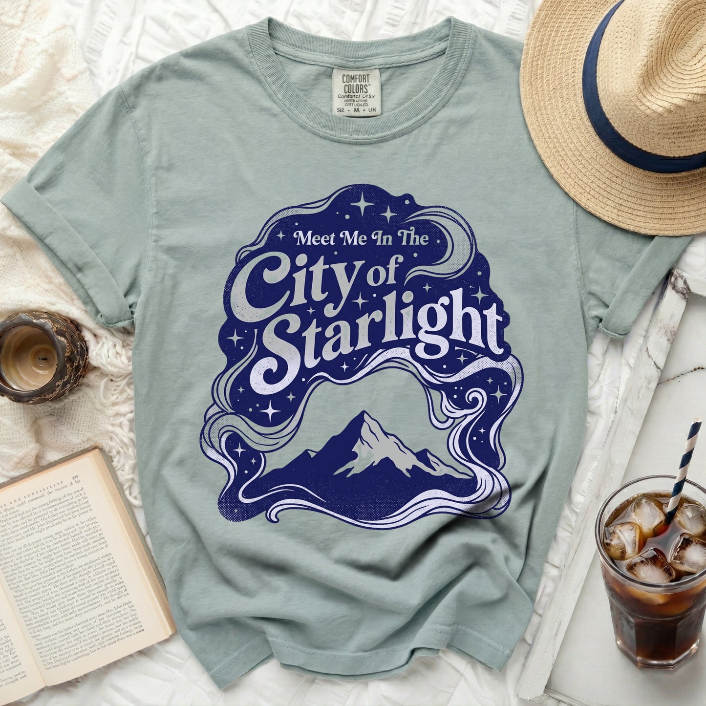 Green t-shirt with "Meet Me In The City of Starlight" graphic and mountain.