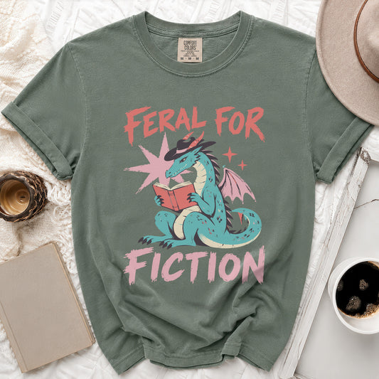 Green t-shirt with a blue dragon reading a book, text "Feral For Fiction".