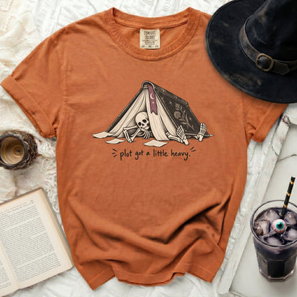 Orange t-shirt featuring a skeleton reading under an open book with text.